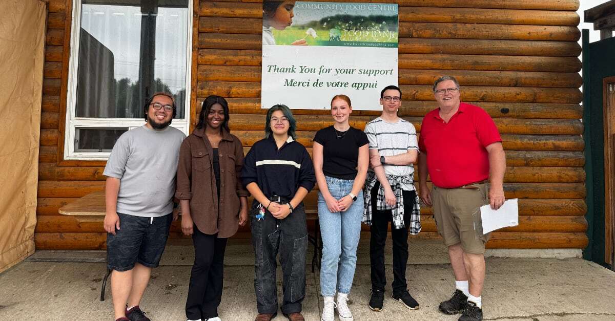Group of 6 individuals standing in front of a sign that says "Community Food Centre: Thank you for your support."